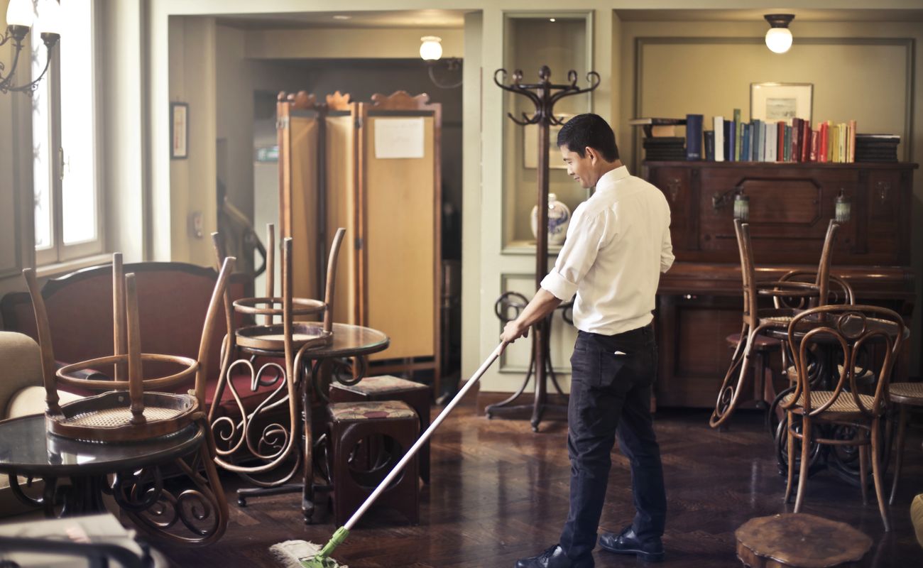 A janitorial worker cleaning the floor of a commercial premises