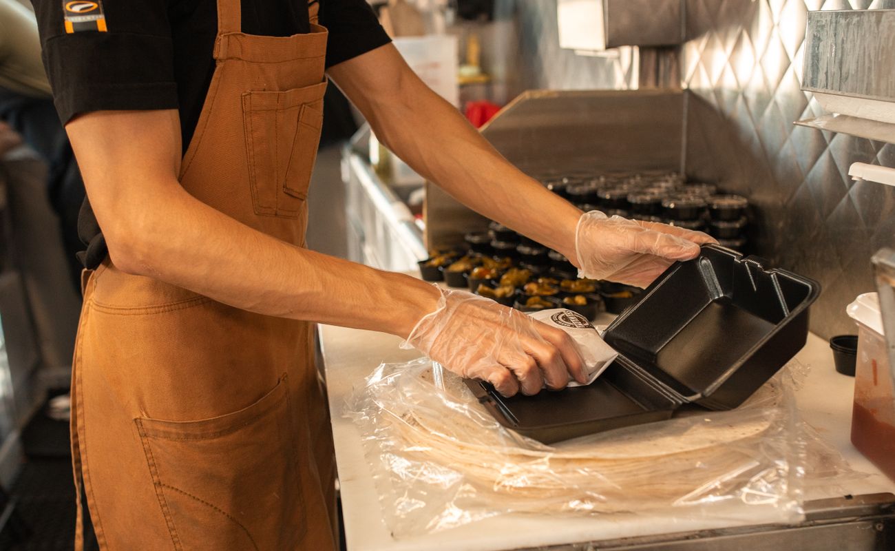 A catering professional preparing packaged takeaway meals